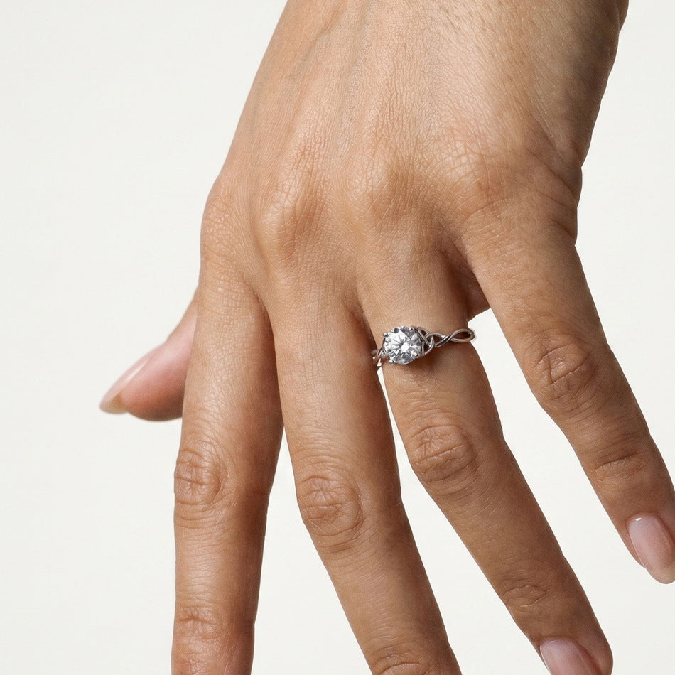 Full hand shot of model wearing round brilliant woven infinity solitaire ring.